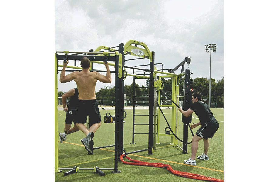Two men using yellow and black modular fitness rig with pull-up bar and rope attachment on outdoor grass field
