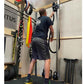 Man wearing black t-shirt and shorts using rope drum attachment mounted on wall in gym setting