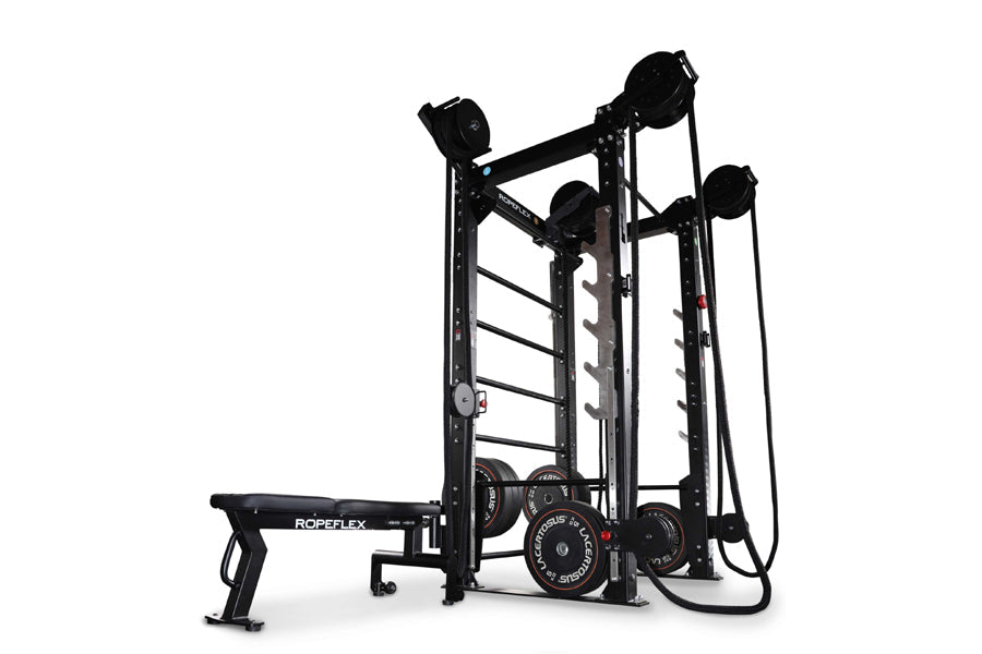 Black multi-functional fitness rack with rope trainer, pulley system, ladder bars, and weight plates on white background