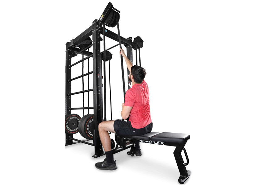 Black cable machine with rope trainer attachment, model wearing pink shirt demonstrating exercise on white background