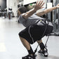 Man wearing gray t-shirt and black shorts with white stripe performing squat exercise with black SKLZ Hopz resistance bands i