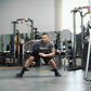 Man performing lateral lunge with SKLZ Lateral Resistor Pro resistance band in gym setting surrounded by exercise equipment