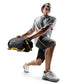 Man wearing gray t-shirt and black shorts holding black and yellow weighted sandbag while exercising on white background