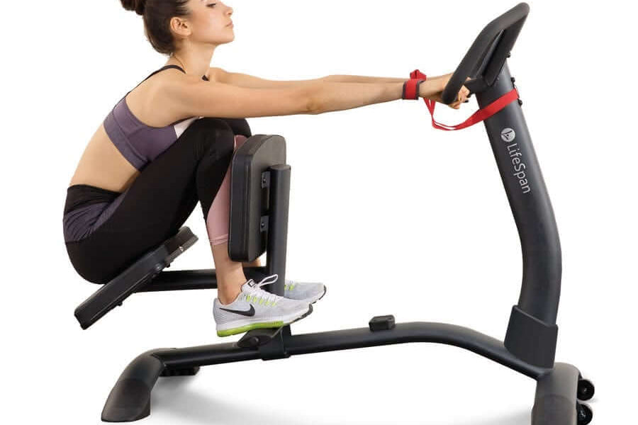 Woman using black LifeSpan stationary bike with red resistance band for stretching, worn by model on white background