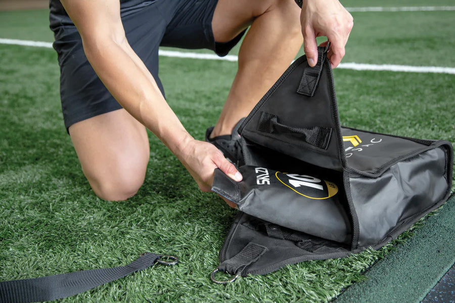Black nylon sports training bag with yellow logo, worn by model on athletic field