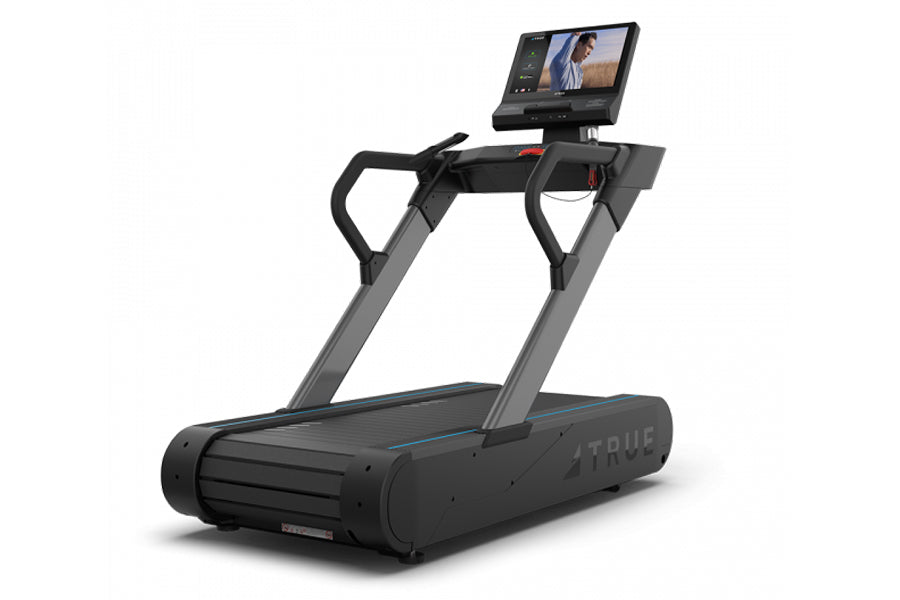 TRUE Stryker Slat Treadmill with black and gray frame, dual handles, and touchscreen display showing workout content on white