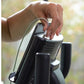 Hand adjusting white and black upright exercise bike seat held outdoors