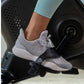 Gray and white knit sneaker with white sole worn by person on Schwinn upright exercise bike pedal