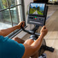 Person using Schwinn 290 recumbent exercise bike with digital display showing scenic mountain road, black frame and console w