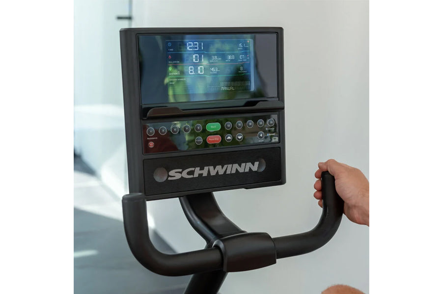 Schwinn 290 recumbent exercise bike with digital display console showing fitness metrics, black frame and handlebars, hand on
