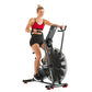 Woman wearing red sports bra and black shorts using black Schwinn Airdyne stationary exercise bike with large fan wheel on wh