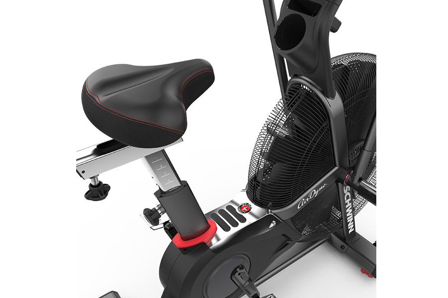 Schwinn Airdyne AD7 stationary exercise bike with black frame, padded seat with red trim, and large front fan wheel on white 
