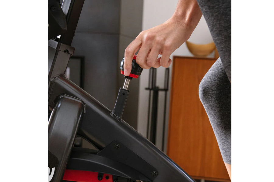 Hand adjusting resistance knob on black Schwinn IC4 indoor cycling bike during workout