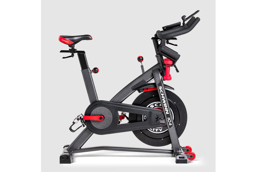 Schwinn IC4 indoor cycling bike with black frame, red and black seat, handlebars, and pedals on white background