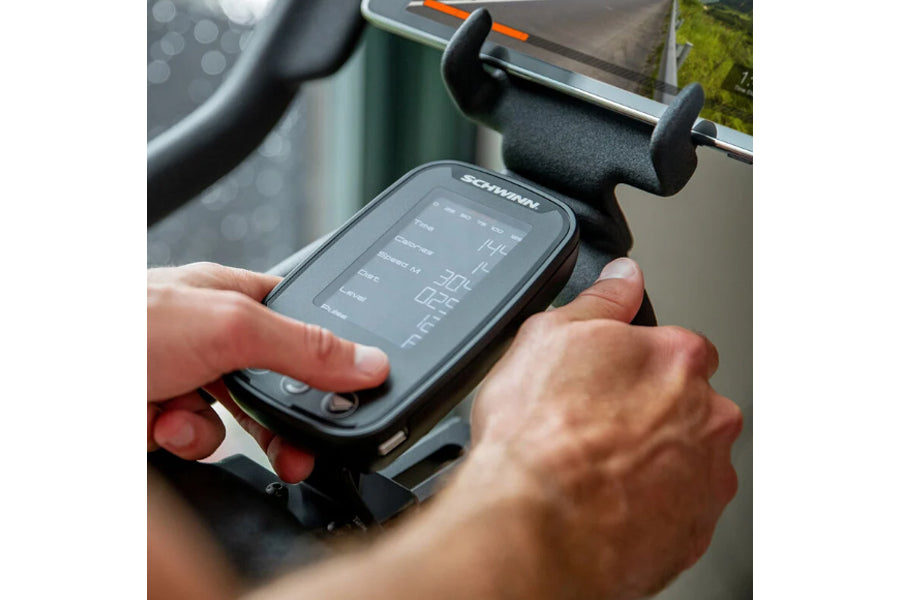 Schwinn IC4 bike display console with digital screen held in user's hands during indoor cycling workout