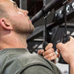 Man using black spiral strength grips on overhead bar, worn in gym setting
