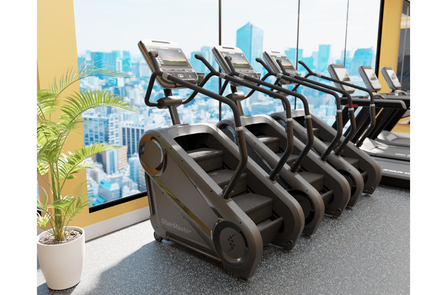 Row of black and gray StairMaster Gauntlet 4G StepMills with digital displays in modern gym with city skyline view