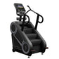 Black StairMaster 8Gx Gauntlet stair stepper with digital console, dual handles, and stepped climbing platform on white backg