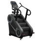 Black StairMaster 8Gx Gauntlet stair stepper with digital display console, handrails, and stepped climbing surface on white b