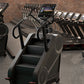 Black and silver StairMaster 8Gx stair stepper with digital display in gym setting surrounded by dumbbells and equipment