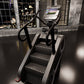 Black and silver StairMaster 8Gx stair stepper with dual handles and digital display screen in gym setting