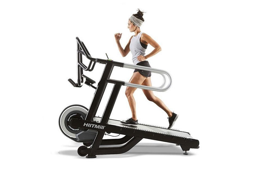 Woman in light blue tank top and black shorts running on black HIITMill treadmill with silver handles against white backgroun