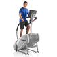 Man wearing blue t-shirt and black shorts using gray StairMaster SM3 StepMill exercise machine with digital display on white 