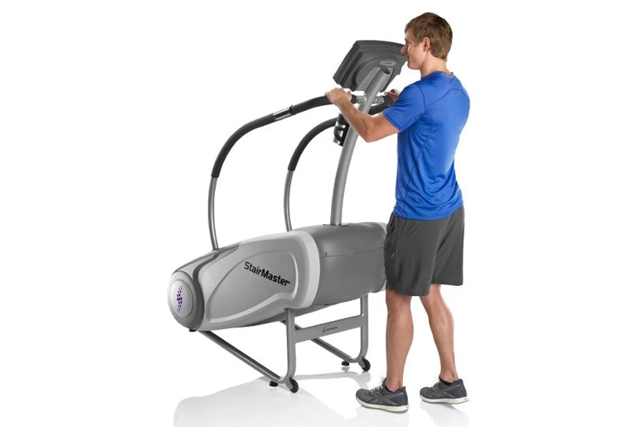 Man in blue shirt using gray StairMaster SM3 StepMill with dual handles on white background