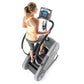 Woman in yellow tank top using gray StairMaster StepMill with digital console display, overhead view