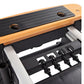 Stamina Pilates Reformer with natural wood frame, black rubber foot platform, and black metal springs on white background