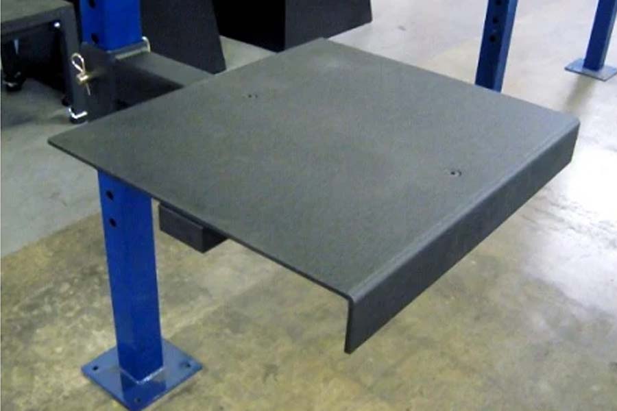 Gray rubber platform attachment with blue steel base support, displayed in warehouse setting