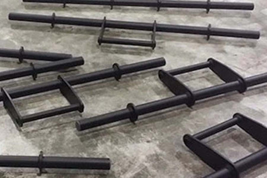 Black steel farmer's walk handles with rectangular frames, displayed on concrete floor