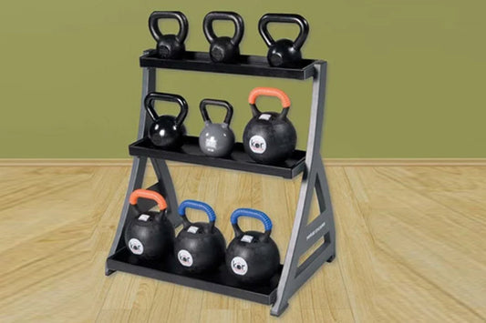 Three-tier kettlebell rack with gray steel frame and black shelves holding nine black kettlebells with colored handles, on wo