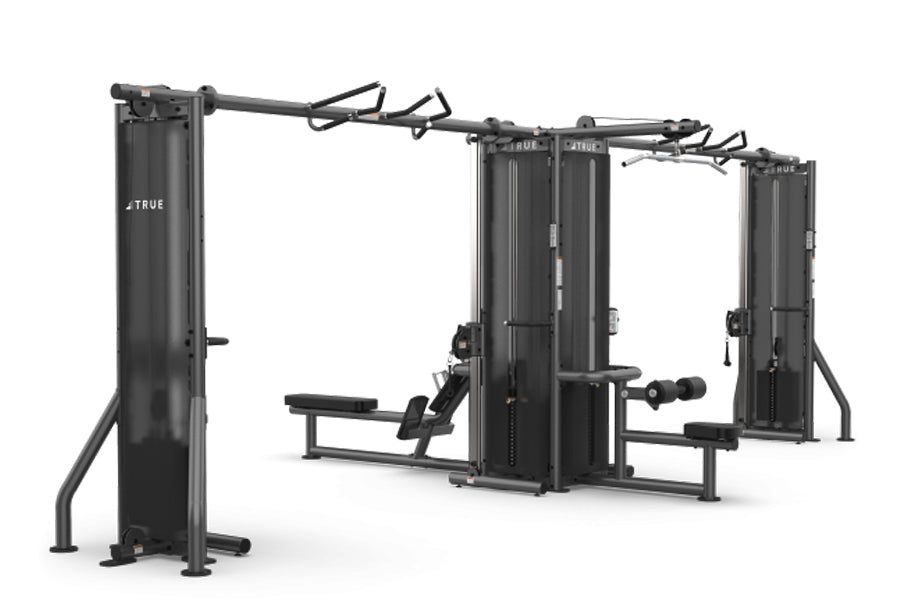 TRUE TMS6000 modular gym system with dual cable crossovers, black steel frame with adjustable arms and benches, on white back