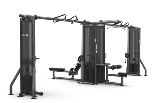 TRUE TMS6000 modular gym system with dual cable crossovers, black steel frame with adjustable arms and benches, on white back