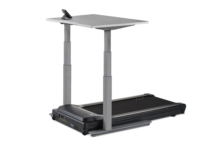 Gray adjustable desk treadmill with black base, dual vertical supports, and gray work surface with clip holder, on white back