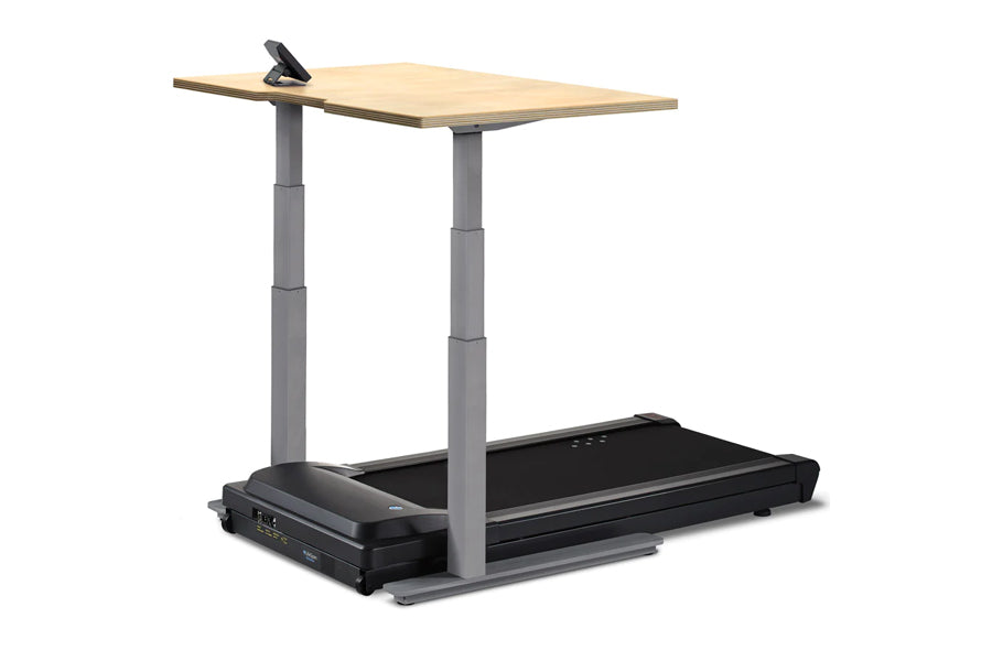 Adjustable-height standing desk with light wood top and gray metal frame mounted above black treadmill base with control pane