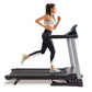 Woman running on black and gray LifeSpan TR2000i folding treadmill wearing white sports bra and black leggings