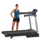 Woman in blue tank top and black shorts standing on black and silver LifeSpan TR3000i folding treadmill with digital console