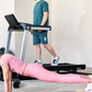 Woman in pink workout set doing plank exercise on floor while man in teal shirt runs on LifeSpan TR3000i folding treadmill in