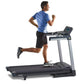 Man running on black and gray folding treadmill with digital console, wearing blue shirt and black shorts
