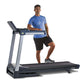Man wearing blue t-shirt and black shorts running on LifeSpan TR4000i folding treadmill with gray frame and black running dec