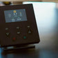 Black fitness tracker device with LCD screen displaying distance, speed, steps, calories, and time, physical buttons labeled 