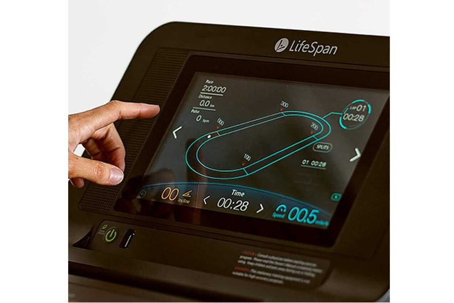 LifeSpan TR6000i treadmill console displaying workout metrics with hand touching touchscreen, showing time, distance, and tea