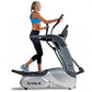 Woman in blue sports bra and black capris using TRUE ES700 elliptical machine with gray and white frame on white background
