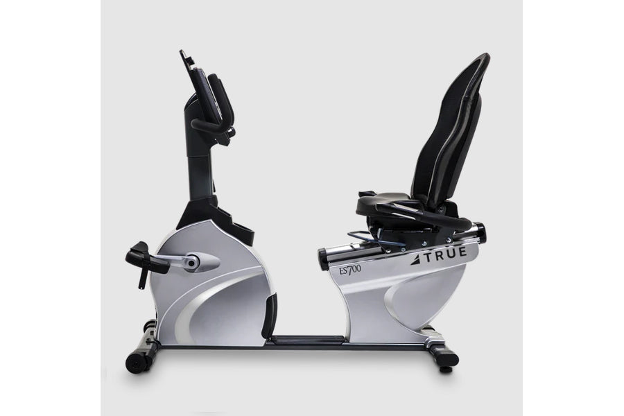 TRUE ES700 recumbent exercise bike with gray and black frame, black handlebar arms, and upright seat on white background