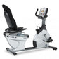 TRUE ES900 upright exercise bike in white and black with digital console, pedals, and black padded seat on white background