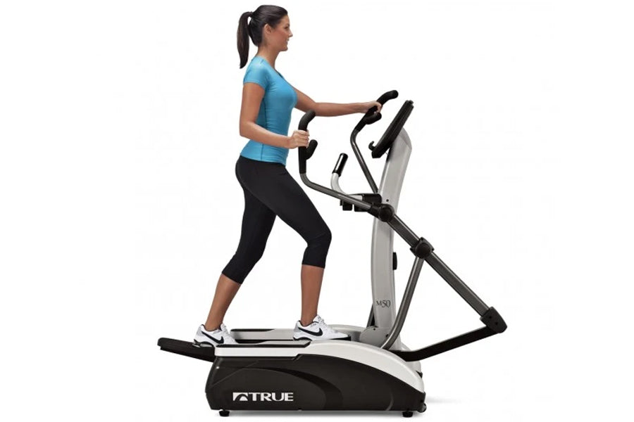 Woman in blue top and black capris using True M50 elliptical machine with white and black frame