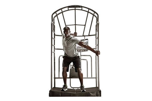 Man exercising on TRUE Stretch training machine with metal frame and black platform, demonstrating stretching position