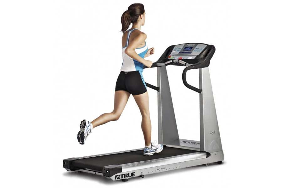 Woman running on TRUE Z5.4 treadmill with gray frame, black belt, and digital console display
